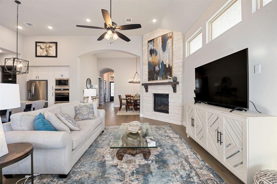 Living room featuring a high ceiling, dark hardwood / wood-style floors, and ceiling fan with notable chandelier