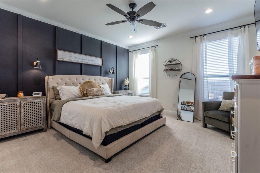 Carpeted bedroom with ceiling fan and ornamental molding