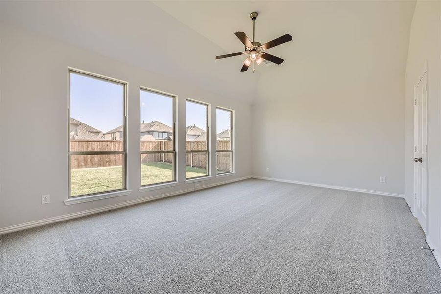 Spare room featuring ceiling fan, high vaulted ceiling, and carpet