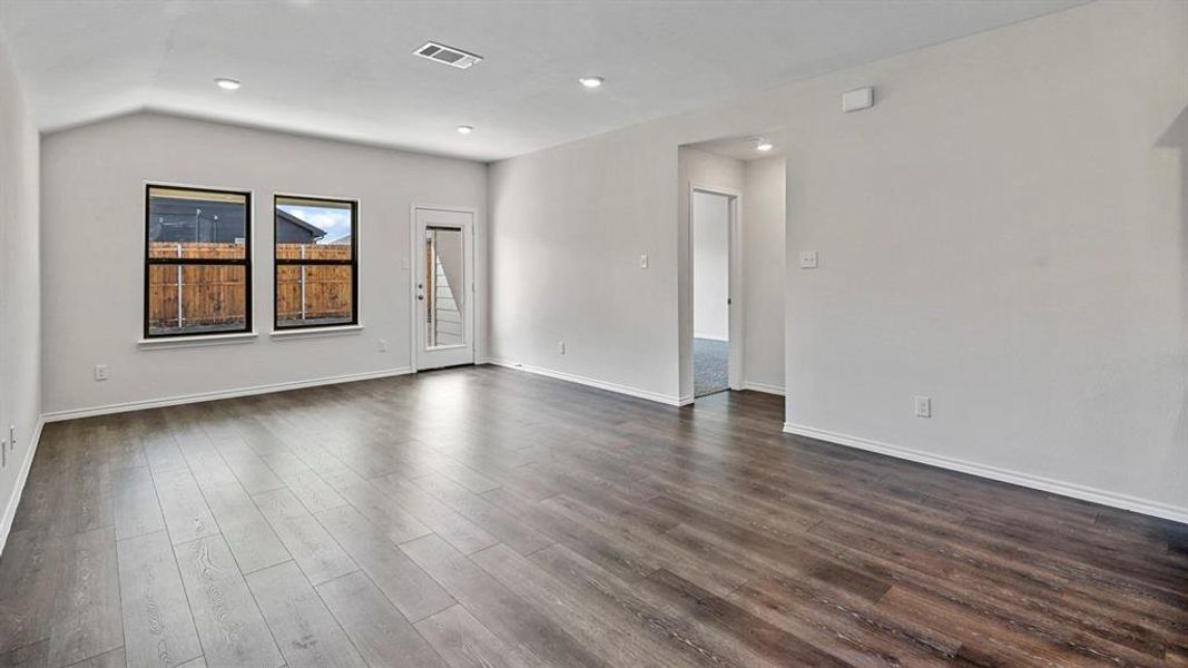 Empty room with dark wood-style flooring, lofted ceiling, and recessed lighting Empty room with dark wood-style flooring, lofted ceiling, and recessed lighting