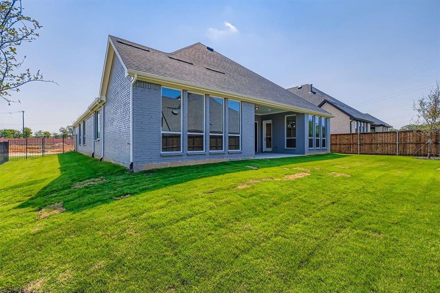 Back of house with a fenced backyard, a patio area, brick siding, and a shingled roof Back of house with a fenced backyard, a patio area, brick siding, and a shingled roof