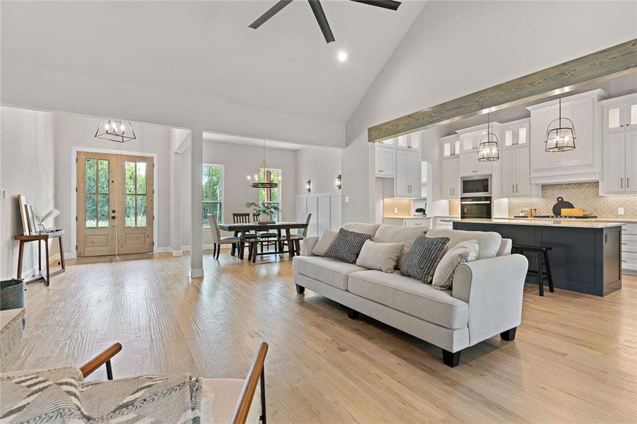 Living room featuring french doors, light wood-type flooring, high vaulted ceiling, and ceiling fan