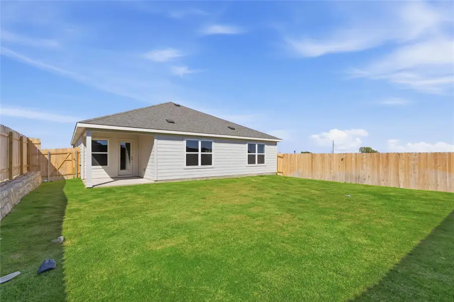 Rear view of house featuring a shingled roof, a patio area, and a fenced backyard