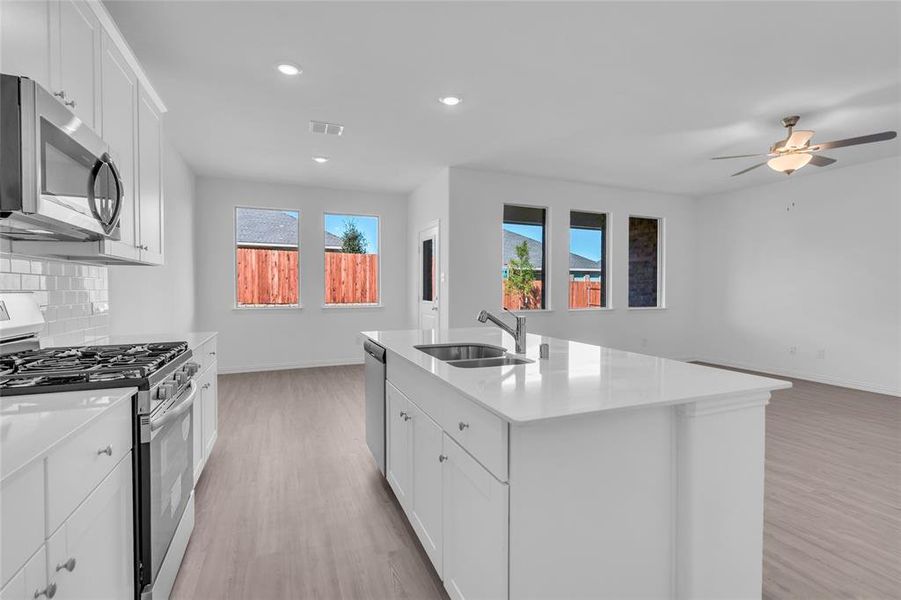 Kitchen featuring an island with sink, stainless steel appliances, sink, and a healthy amount of sunlight