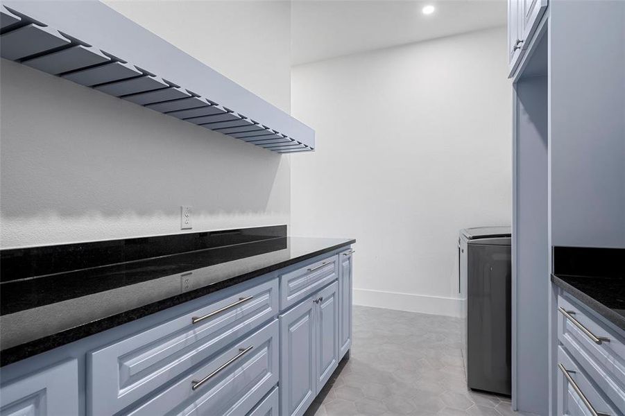 Kitchen with extractor fan, dark stone counters, light tile patterned flooring, and separate washer and dryer Kitchen with extractor fan, dark stone counters, light tile patterned flooring, and separate washer and dryer