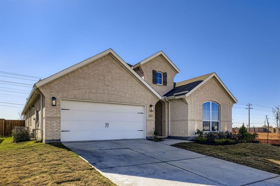 View of front of home featuring driveway, brick siding, and an attached garage