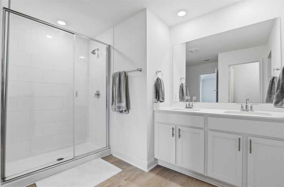 Contemporary bathroom featuring a glass-enclosed shower with white subway tile, a dual vanity with white cabinetry, light countertops, and a full-width mirror