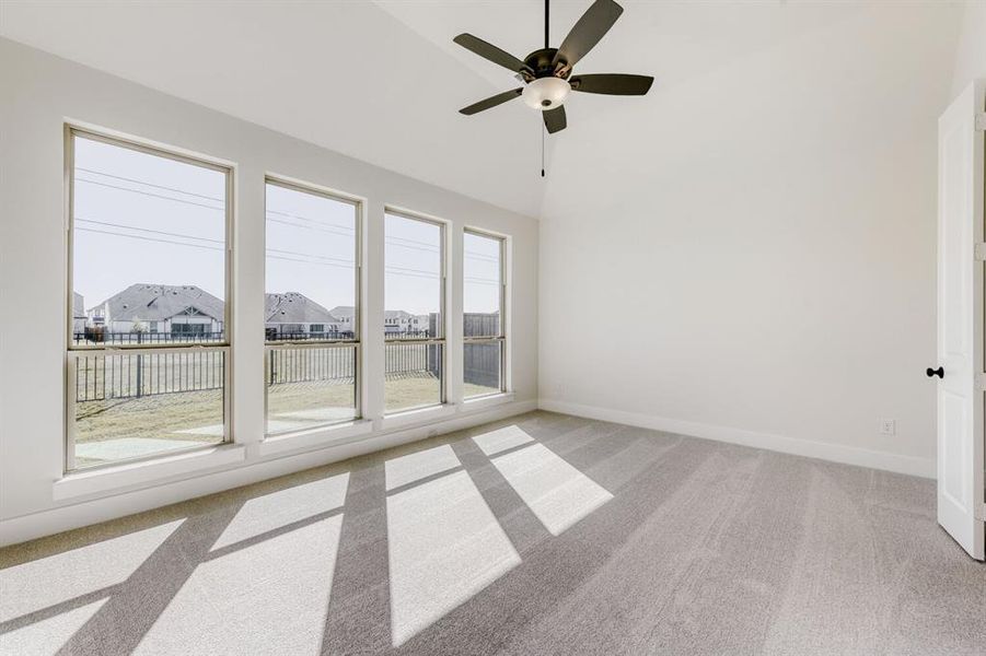Empty room featuring light colored carpet, ceiling fan, lofted ceiling, and a residential view