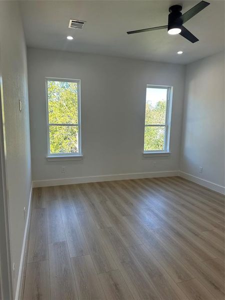 Empty room with ceiling fan and light wood-type flooring