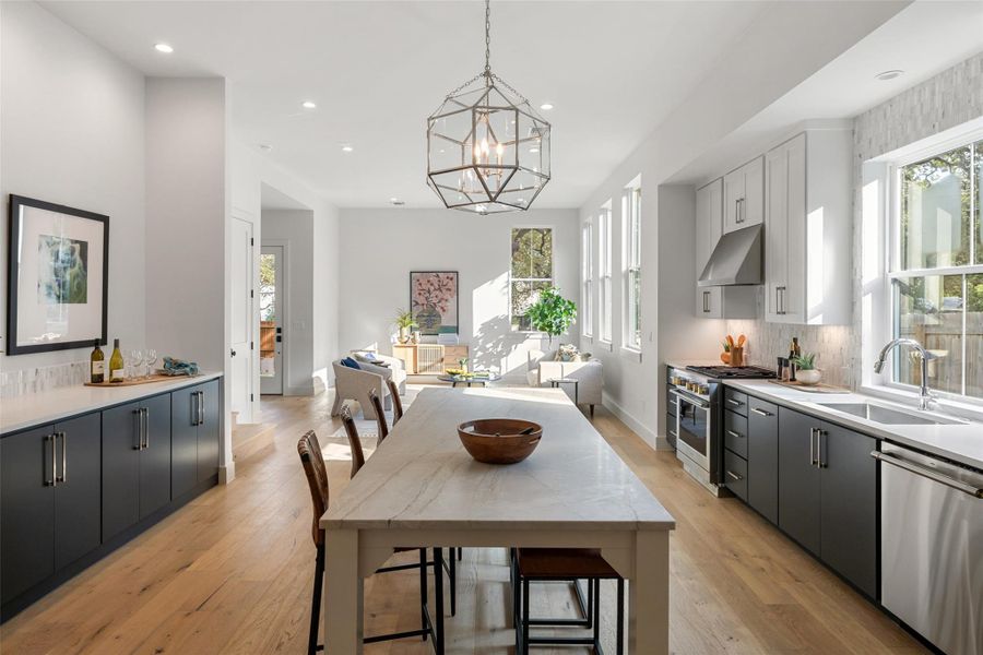 Kitchen featuring pendant lighting, white cabinets, stainless steel appliances, decorative backsplash, and sink