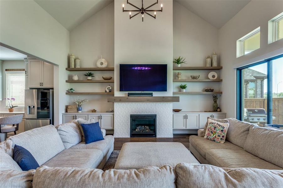Living room featuring high vaulted ceiling, a glass covered fireplace, wood finished floors, and a chandelier Living room featuring high vaulted ceiling, a glass covered fireplace, wood finished floors, and a chandelier