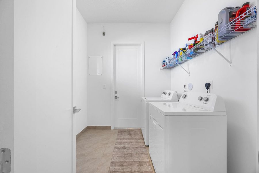 Laundry room with washer and dryer and light tile patterned flooring