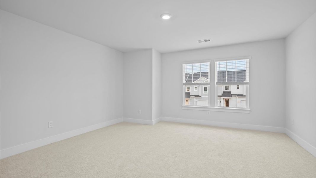 Elegant bedroom retreat featuring soft carpet and oversized windows that create a bright, welcoming space