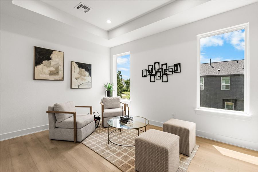 This view shows the size and natural light of the upper lounge. Large windows look out over the neighborhood and keep the room bright, while the open layout easily fits multiple chairs, accent cubes, and a coffee table.