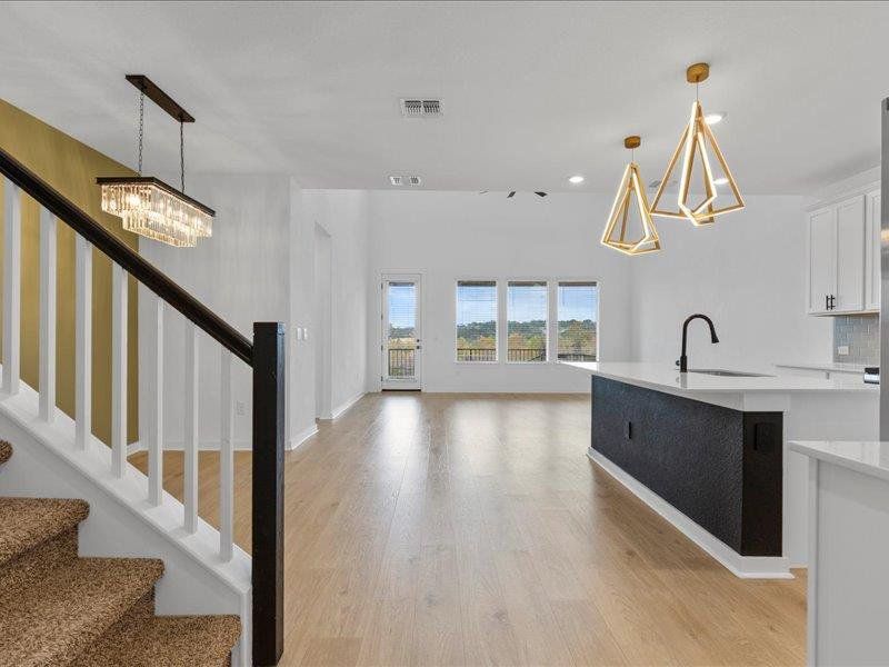 Kitchen featuring a chandelier, pendant lighting, white cabinetry, open floor plan, and light wood-type flooring