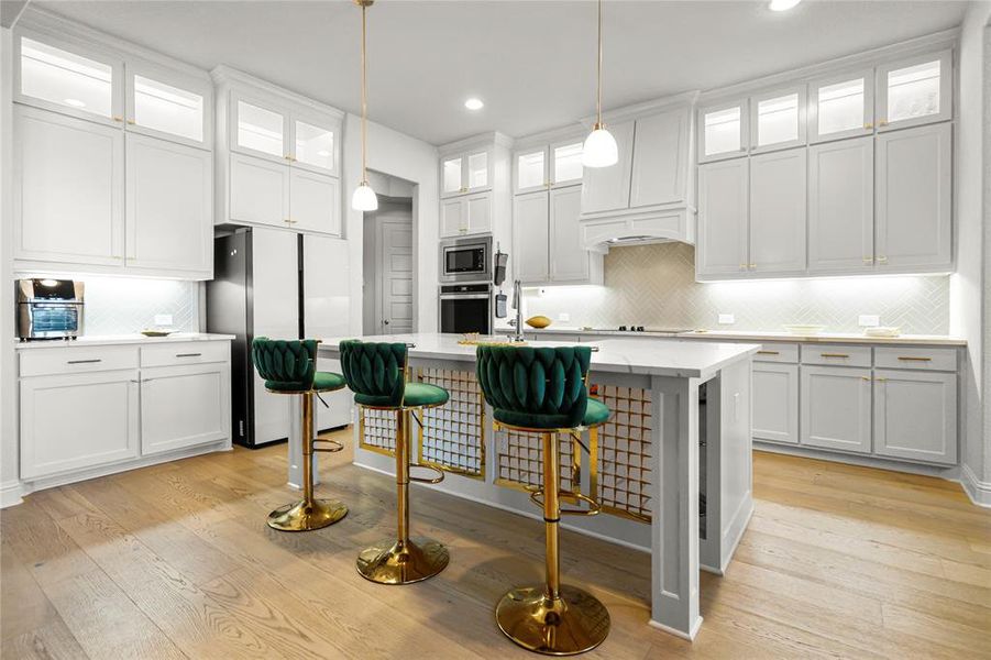 Kitchen with decorative backsplash, glass insert cabinets, appliances with stainless steel finishes, light wood-style floors, and recessed lighting Kitchen with decorative backsplash, glass insert cabinets, appliances with stainless steel finishes, light wood-style floors, and recessed lighting
