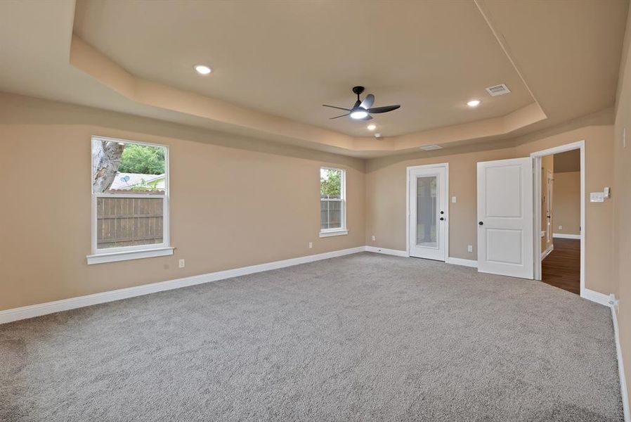 Empty room featuring ceiling fan, carpet floors, a tray ceiling, baseboards, and recessed lighting Empty room featuring ceiling fan, carpet floors, a tray ceiling, baseboards, and recessed lighting