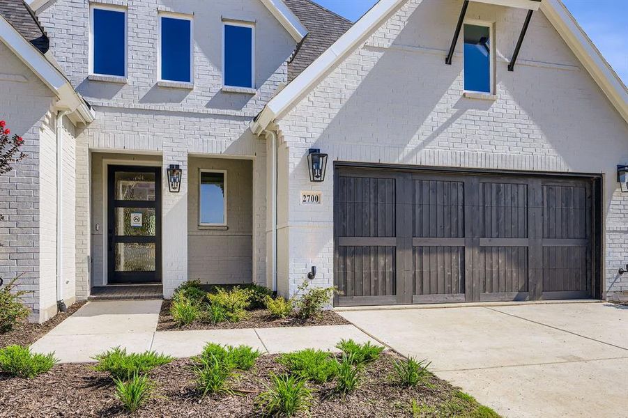 View of front facade with brick siding, driveway, and an attached garage