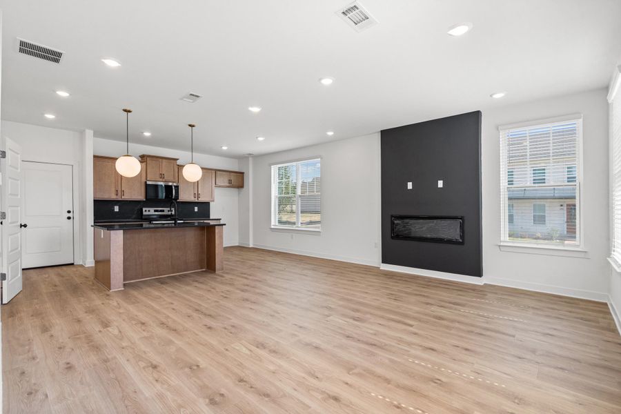 Open-concept living space featuring wood-finish flooring, recessed lighting, and a modern fireplace