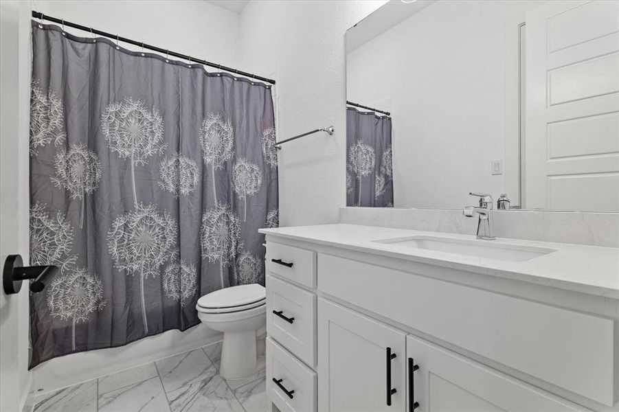 Bathroom with vanity, shower / tub combo, and light marble finish flooring Bathroom with vanity, shower / tub combo, and light marble finish flooring