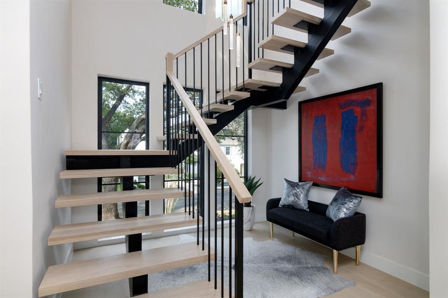 Stairs with a high ceiling, a wealth of natural light, and hardwood / wood-style floors