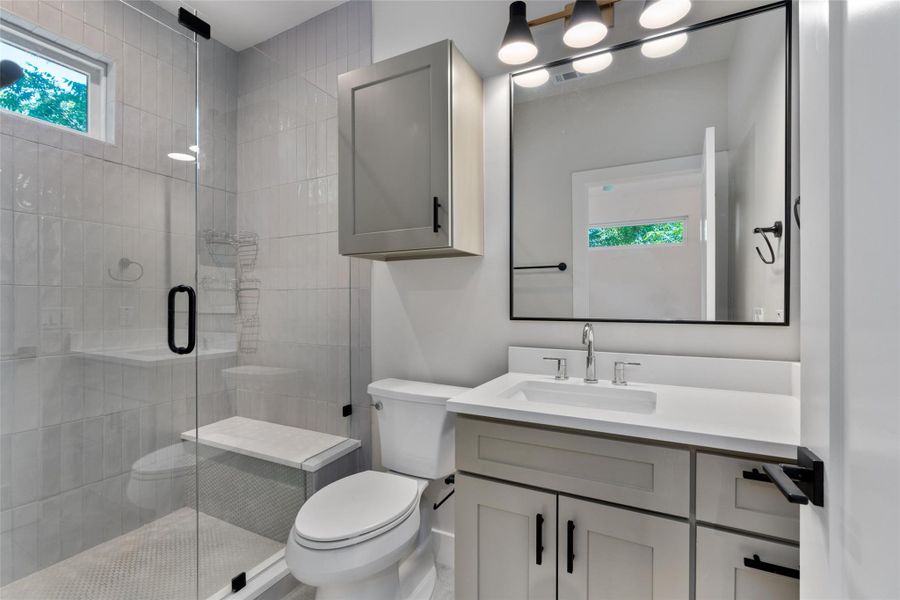 Contemporary primary bathroom featuring a frameless glass shower enclosure with a built-in bench, a window, and vertical subway tile Contemporary primary bathroom featuring a frameless glass shower enclosure with a built-in bench, a window, and vertical subway tile