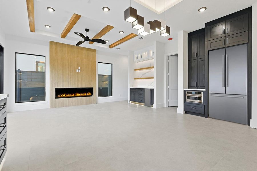 The open-concept living area features natural wood ceiling beams, integrated kitchen appliances, and designer box-pendant lighting.