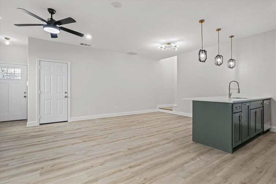 Bar featuring ceiling fan, sink, decorative light fixtures, green cabinetry, and light hardwood / wood-style floors