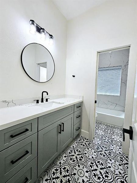 Jack & Jill full bathroom with plenty of cabinets, and the floor design continues from the primary bathroom.