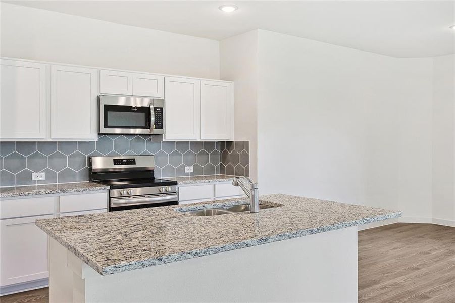 Kitchen with white cabinets, light hardwood / wood-style floors, appliances with stainless steel finishes, and sink