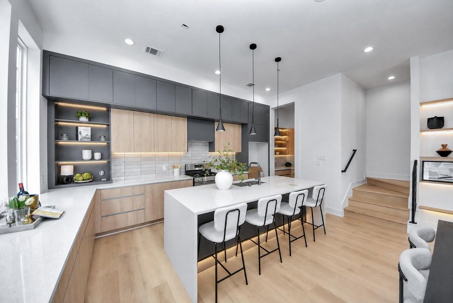 Modern kitchen featuring an oversized waterfall island with seating for four and sleek two-tone cabinetry.