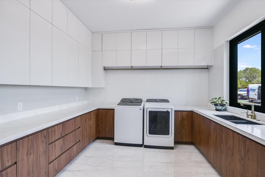 Incredible Laundry room featuring washer and clothes dryer, light marble look tile floors, and loads of cabinet as well as a sink and window Incredible Laundry room featuring washer and clothes dryer, light marble look tile floors, and loads of cabinet as well as a sink and window
