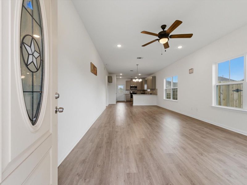 The welcoming foyer sets the tone with high ceilings, sleek vinyl plank flooring, and a bright, open flow into the main living spaces.