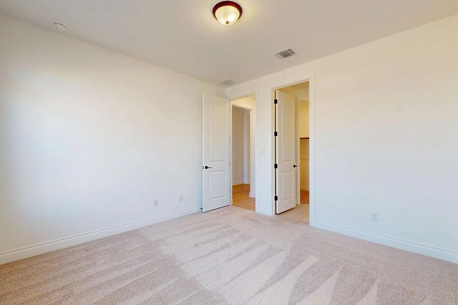 This room features neutral-toned carpeting, white walls, and a ceiling light fixture