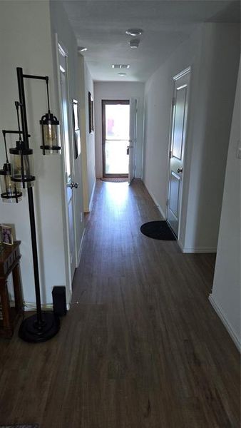 Hallway featuring wood-finish flooring, white trim, recessed lighting, and a white paneled door