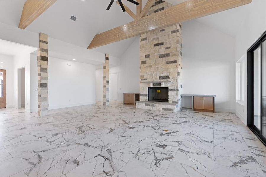A spacious great room showcases a stone fireplace, exposed beam ceiling, and a wall of glass doors. A spacious great room showcases a stone fireplace, exposed beam ceiling, and a wall of glass doors.