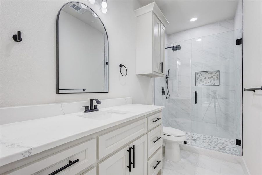 Bathroom with vanity, toilet, and a shower with shower door