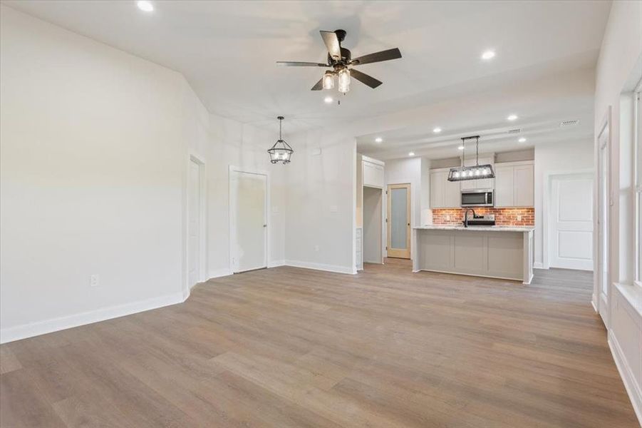 Unfurnished living room featuring recessed lighting, light wood-type flooring, a chandelier, and ceiling fan