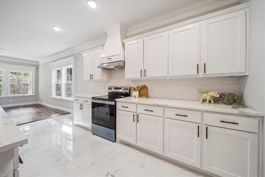 Kitchen featuring tasteful backsplash, stainless steel electric range, crown molding, white cabinetry, and light stone counters