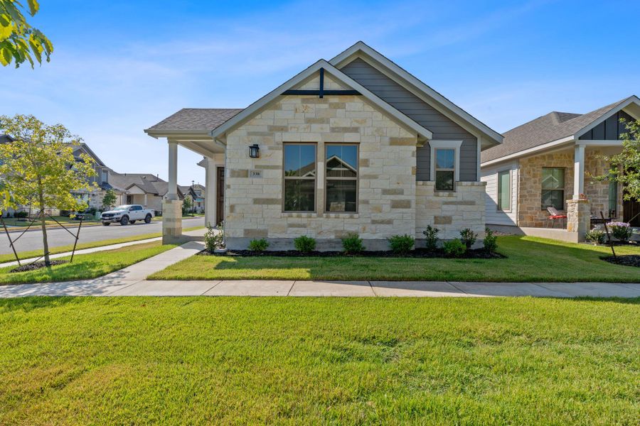 View of front of home featuring a front lawn, stone siding, and roof with shingles View of front of home featuring a front lawn, stone siding, and roof with shingles