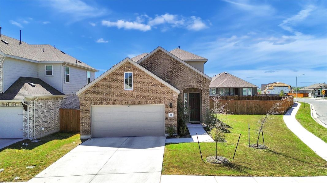 This charming two-story brick home features a neatly manicured front yard, a spacious two-car garage, and a welcoming arched entryway. It's situated in a quiet neighborhood with a curved sidewalk and offers ample natural light and curb appeal.
