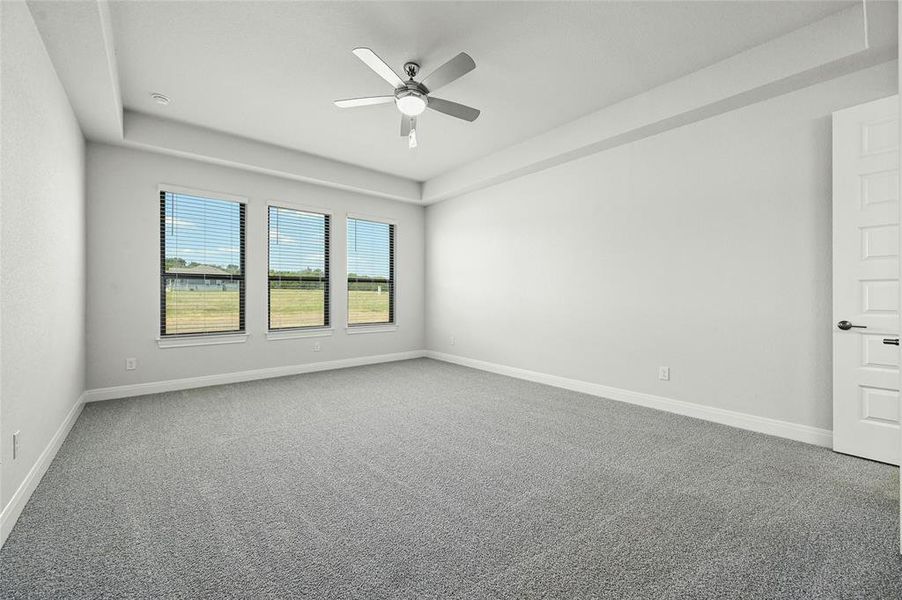 Huge master bedroom with tall tray ceilings and ceiling fan.