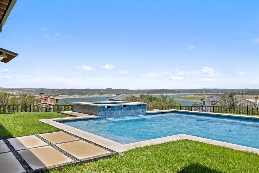 View of swimming pool featuring a fenced backyard, a patio area, a pool with connected hot tub, and a water view