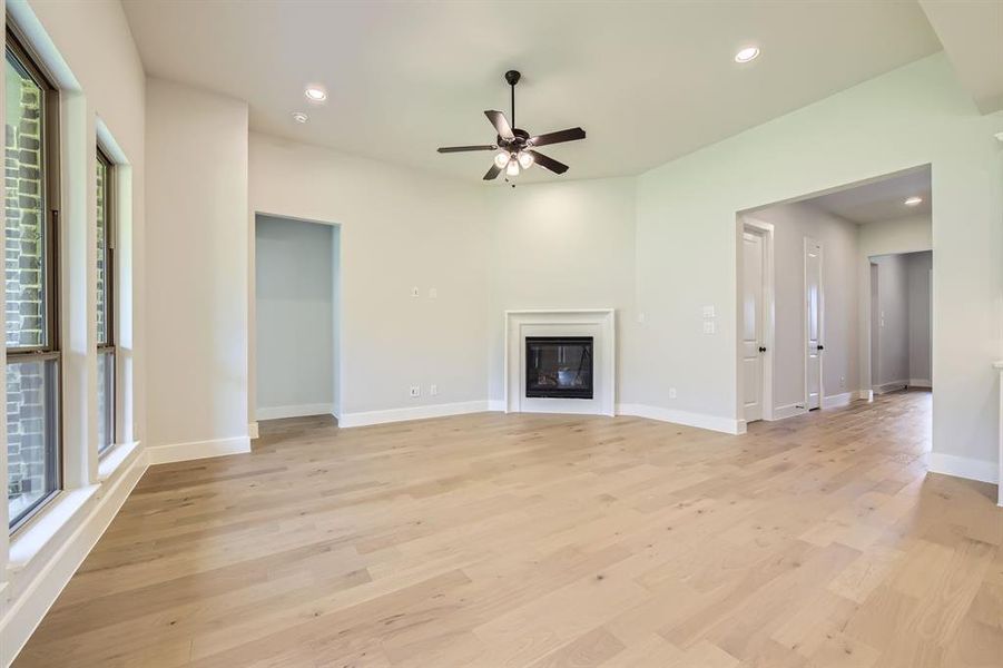 Unfurnished living room with ceiling fan, light wood-style flooring, recessed lighting, and a glass covered fireplace Unfurnished living room with ceiling fan, light wood-style flooring, recessed lighting, and a glass covered fireplace