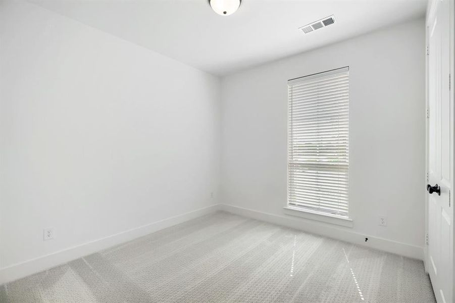 Carpeted interior room featuring a single window with horizontal blinds, white baseboards, and a flush-mount ceiling light
