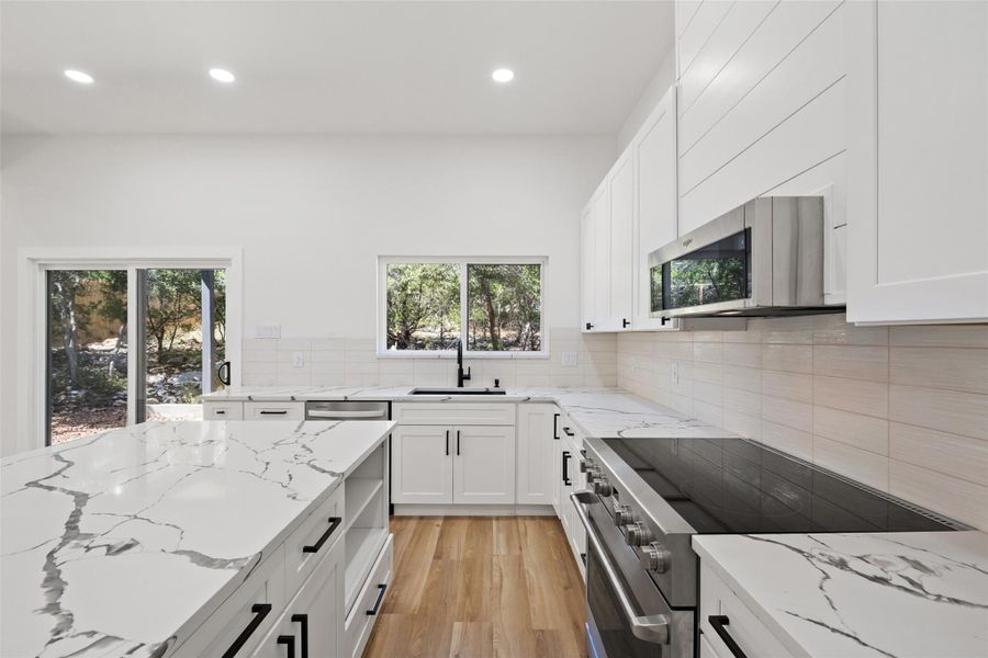 Kitchen with stainless steel appliances, recessed lighting, light stone countertops, white cabinets, and light wood-style flooring Kitchen with stainless steel appliances, recessed lighting, light stone countertops, white cabinets, and light wood-style flooring