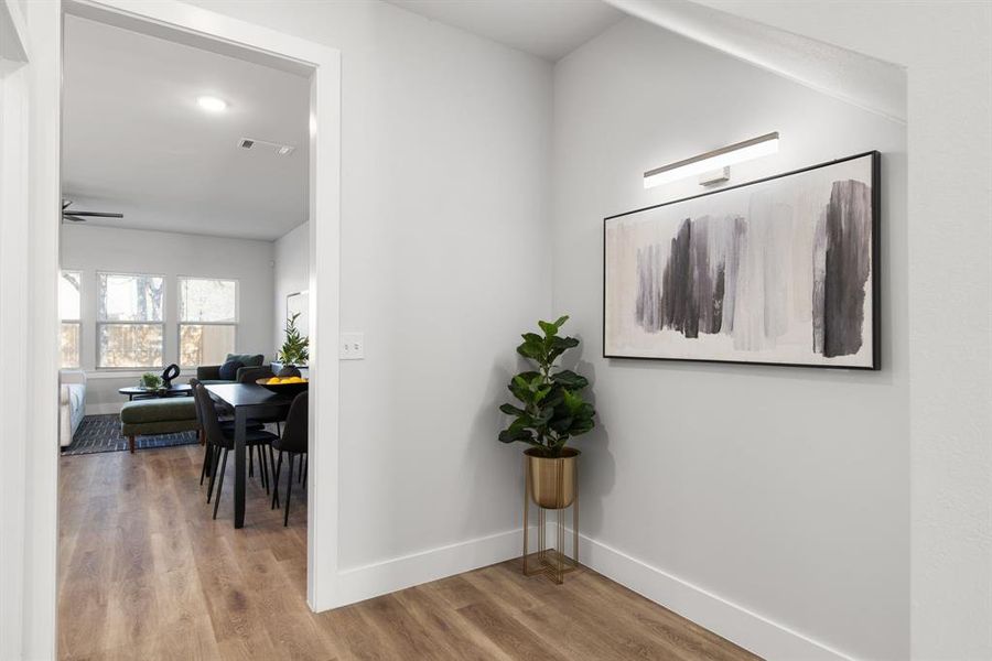 Hall with visible vents, baseboards, and wood finished floors