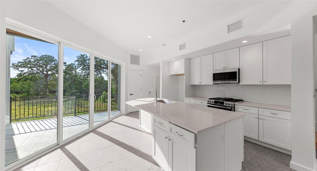 The kitchen's oversized island and stone counters invite gathering — pour a glass of wine, set out a board, and let conversation flow while you cook. Model No. 104 Shown.