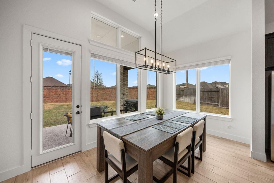 Framed by tall windows and a contemporary linear chandelier, the dining space is filled with natural light and positioned beside direct patio access.