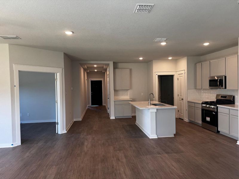 Kitchen with appliances with stainless steel finishes, tasteful backsplash, dark wood-style floors, a center island with sink, and recessed lighting